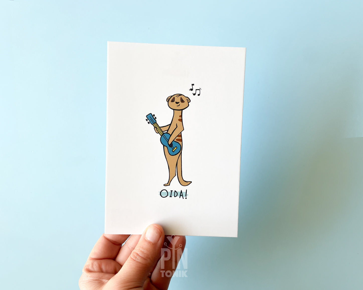 Card with a cartoon meerkat playing a guitar on a blue gradient background