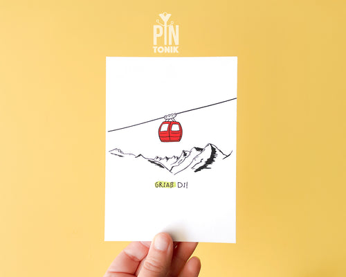 Premium postcard with an original illustration of a red cable car and the text 'Griaß Di!', shown against a vibrant yellow background with a light blue envelope.