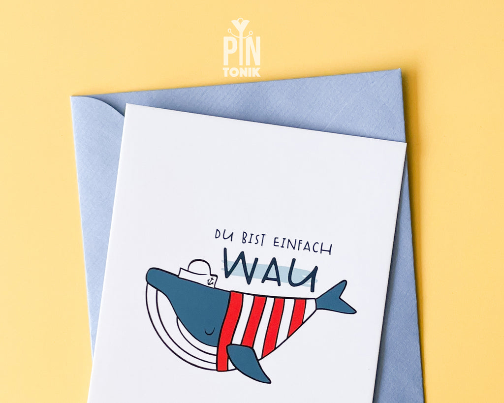 Premium postcard with an original illustration of a blue whale wearing a red striped shirt and a sailor hat with the text 'DU BIST EINFACH WAU', shown with a light blue envelope.