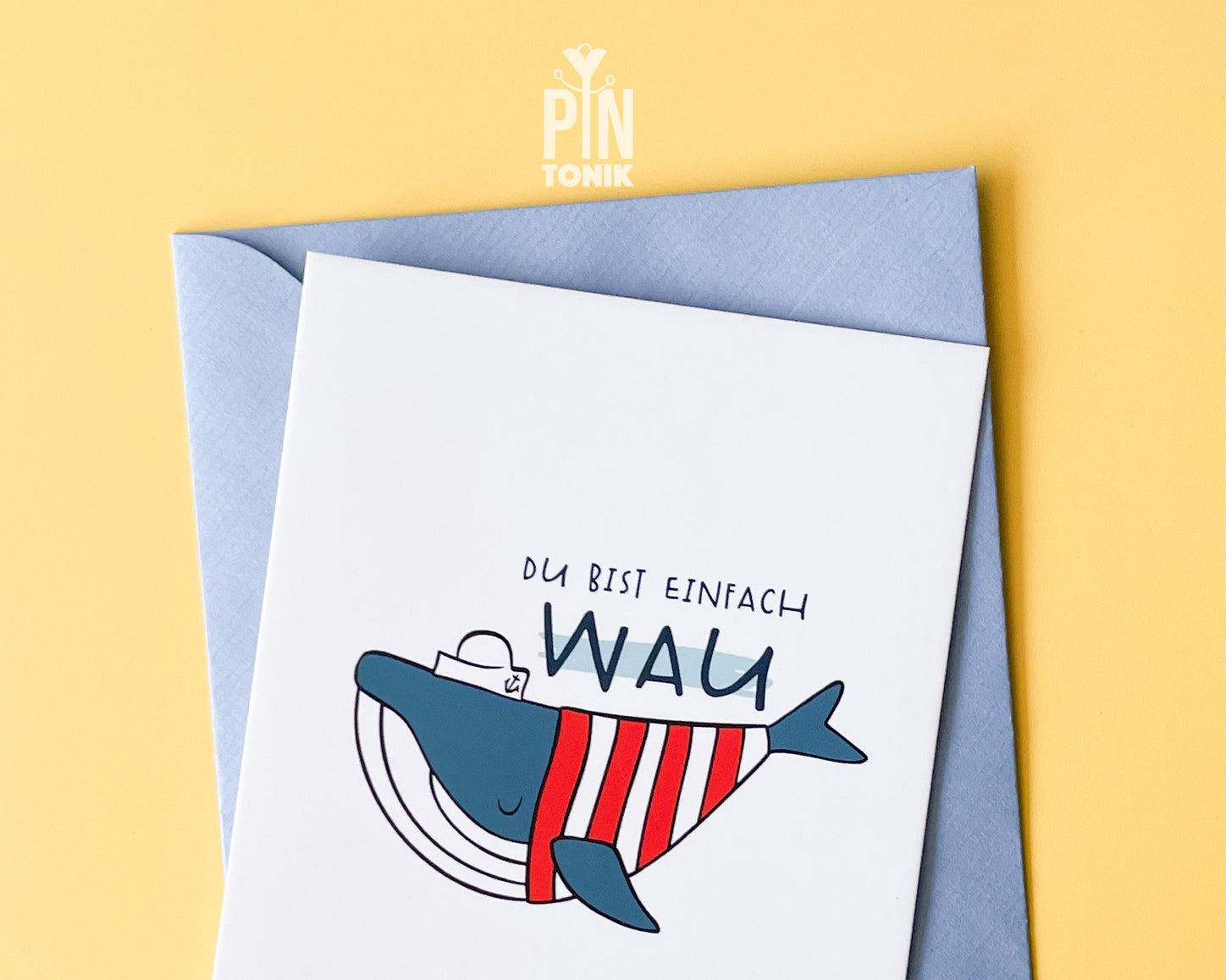 Premium postcard with an original illustration of a blue whale wearing a red striped shirt and a sailor hat with the text 'DU BIST EINFACH WAU', shown with a light blue envelope.