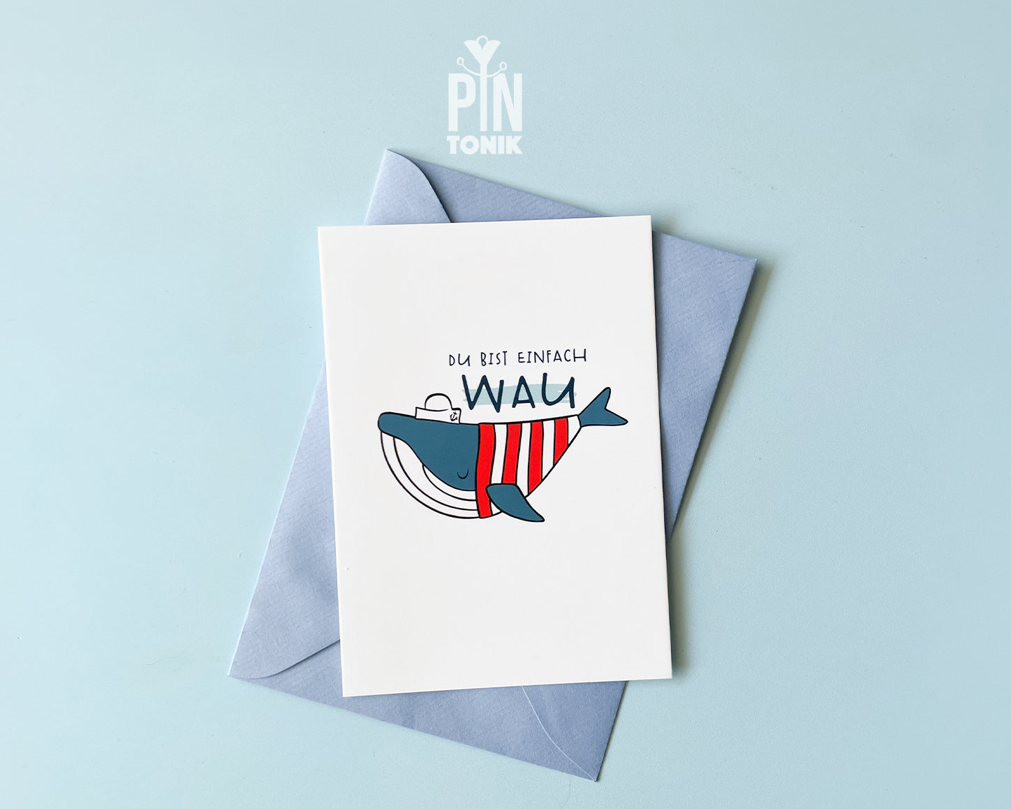 Premium postcard with an original illustration of a blue whale wearing a red striped shirt and a sailor hat with the text 'DU BIST EINFACH WAU', shown with a light blue envelope.