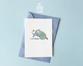Premium postcard featuring Moji the Chameleon, the PinTonik mascot, catching a butterfly with the text 'HAB DICH!', shown with a luxury light blue envelope.