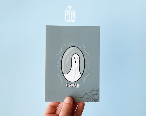 Premium grey postcard with an original illustration of a ghost in a mirror and the text 'BOO!', shown on a light blue background.