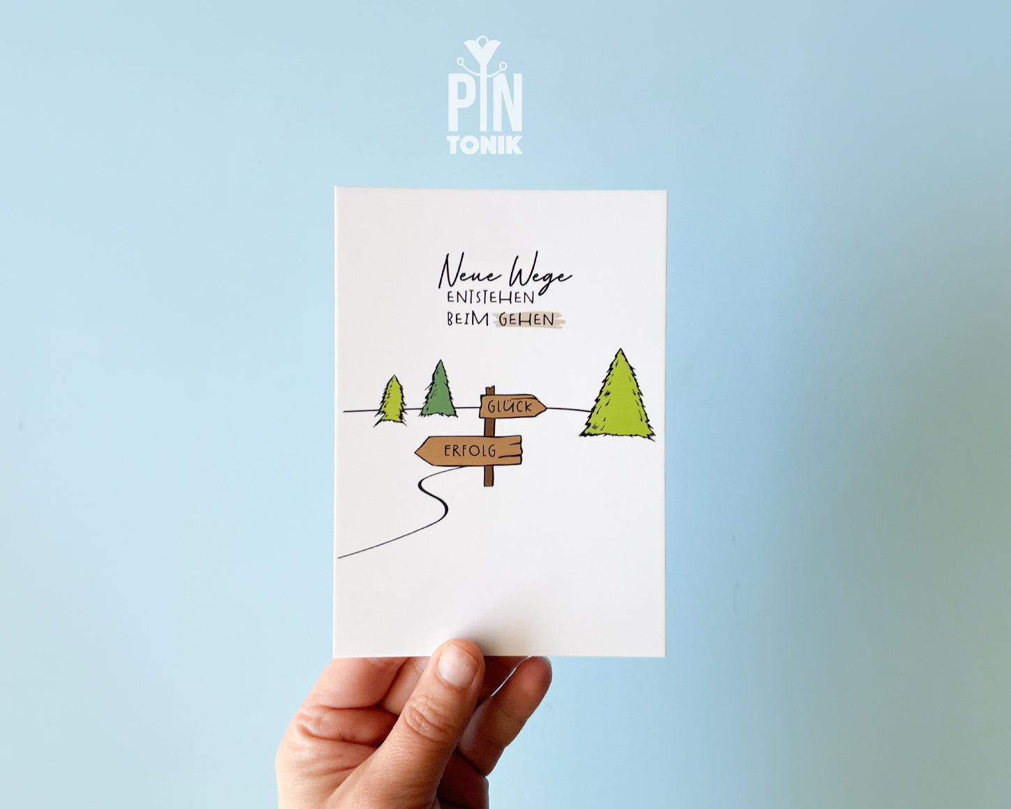 Premium postcard with an original illustration of a forest path and a signpost pointing to 'GLÜCK' and 'ERFOLG' with the text 'Neue Wege entstehen BEIM GEHEN'.