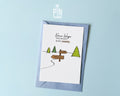 Premium postcard with an original illustration of a forest path and a signpost pointing to 'GLÜCK' and 'ERFOLG' with the text 'Neue Wege entstehen BEIM GEHEN', shown with a light blue luxury envelope.