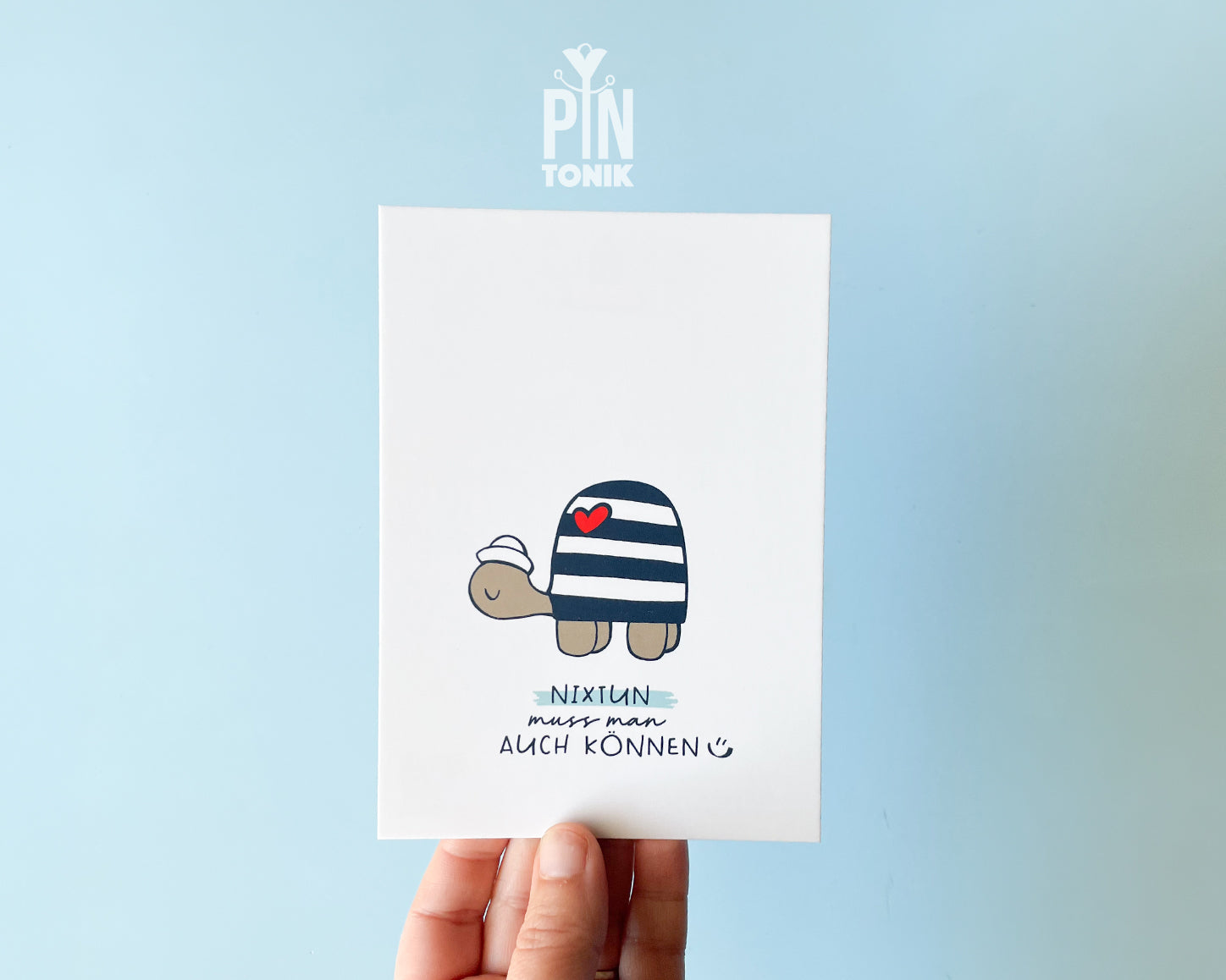 Premium postcard with an original illustration of a turtle wearing a sailor hat and striped shirt with a red heart, featuring the text 'NIXTUN muss man AUCH KÖNNEN'.