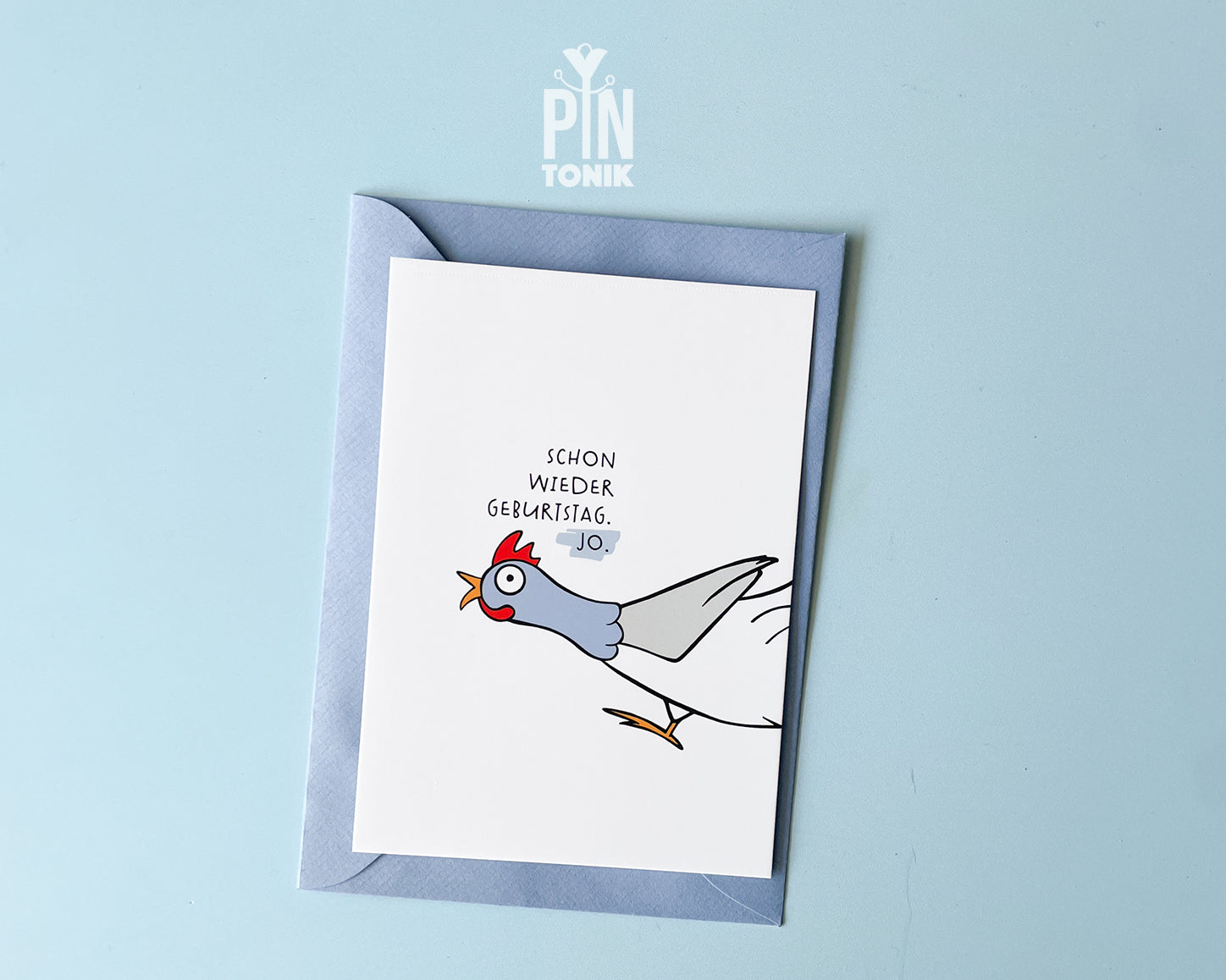Premium postcard with an original illustration of a chicken and the German text 'SCHON WIEDER GEBURTSTAG. JO.', shown against a blue background with a light blue envelope