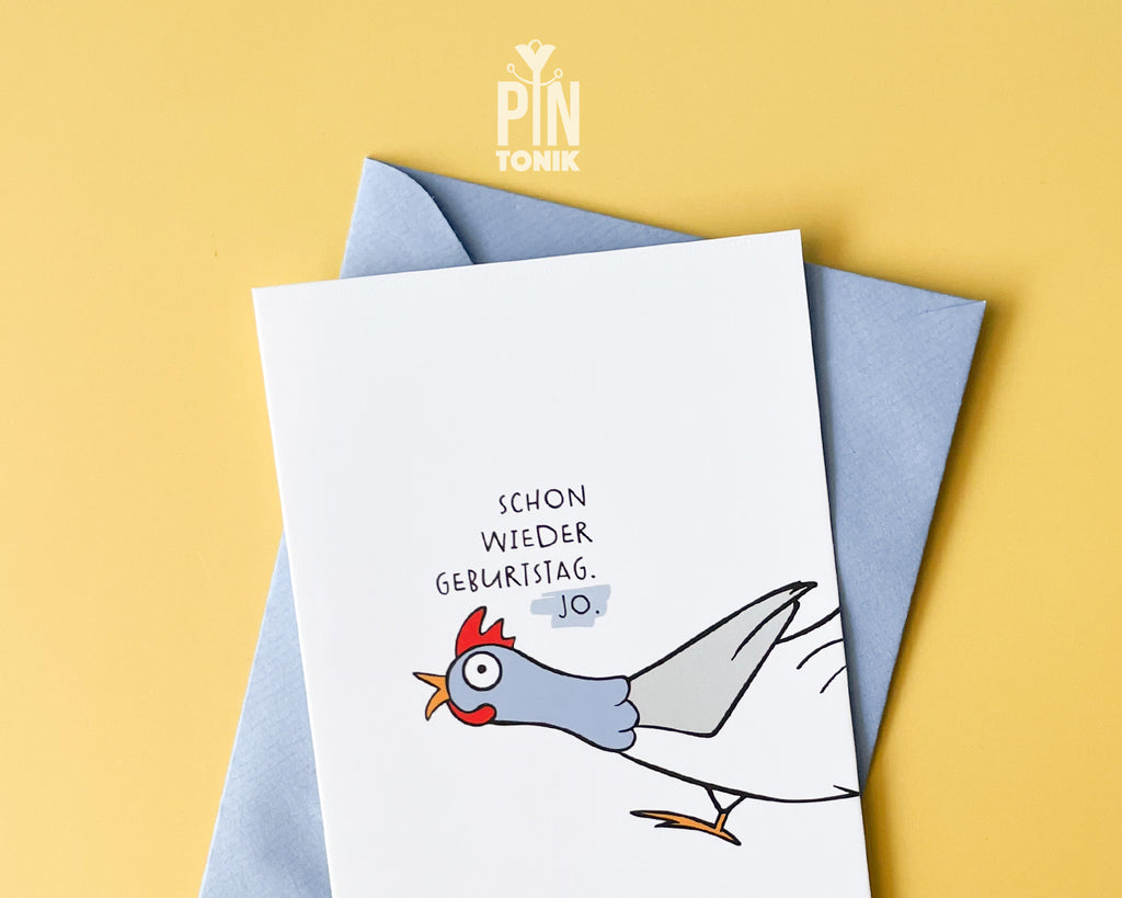 Premium postcard with an original illustration of a chicken and the German text 'SCHON WIEDER GEBURTSTAG. JO.', shown against a yellow background with a light blue envelope