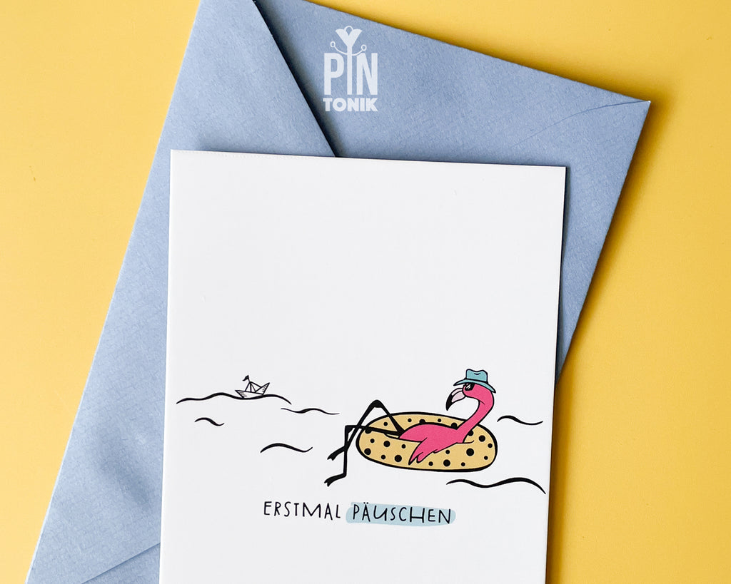 Premium postcard with an original illustration of a flamingo in a polka-dot floatie with the text 'ERSTMAL PÄUSCHEN', shown with a light blue luxury envelope on yellow background.