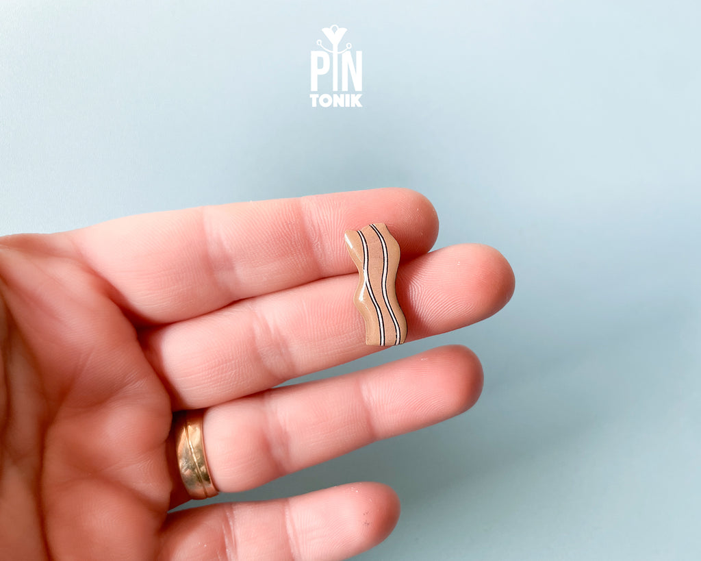 Hand-painted wavy wooden bacon strip pin with tan and white marbled details and a high-gloss finish