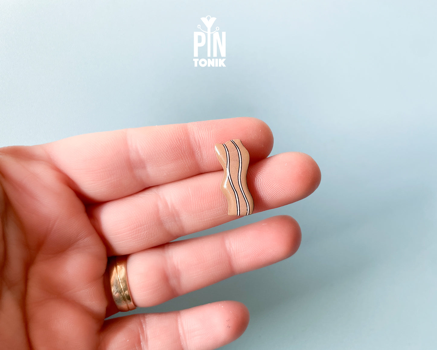 Hand-painted wavy wooden bacon strip pin with tan and white marbled details and a high-gloss finish