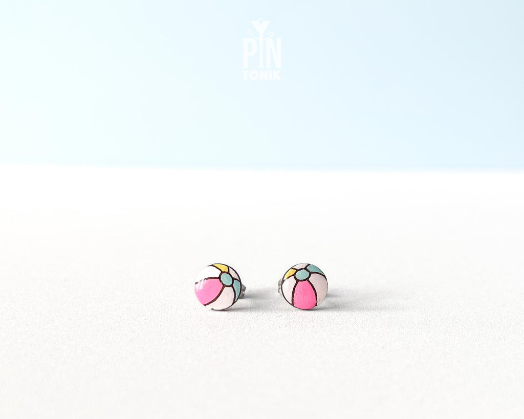 Handmade wooden beach ball stud earrings featuring a cheerful striped pattern of pink, white, and gray panels by PinTonik.