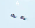 "Handmade wooden bicycle stud earrings illustrated in retro purple and blue shades by PinTonik."
