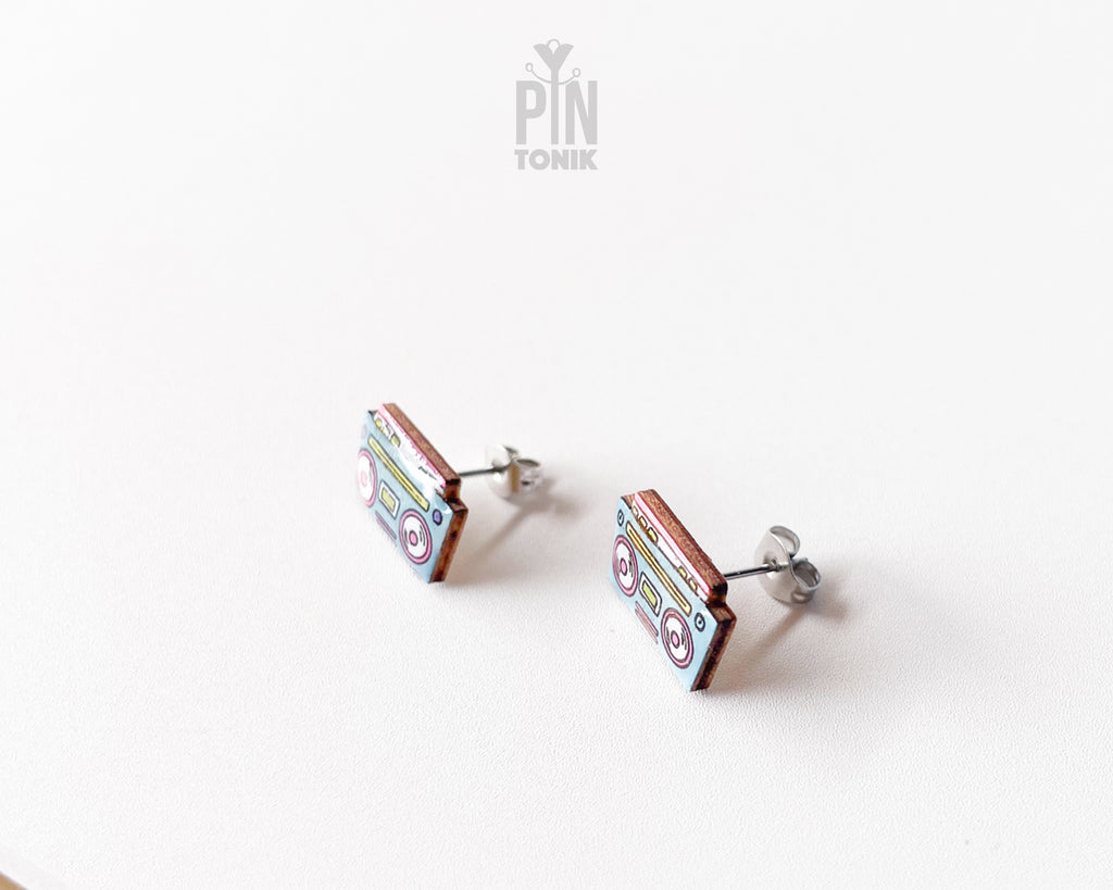 A pair of rectangular wooden stud earrings shaped like retro cassette tapes, featuring colorful handpainted details and stainless steel posts, displayed on a clean white surface.