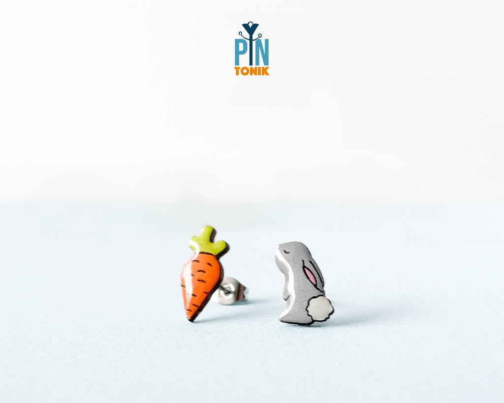 Mismatched hand-painted wooden stud earrings featuring a grey bunny and a bright orange carrot