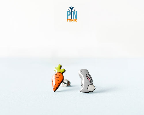 Mismatched hand-painted wooden stud earrings featuring a grey bunny and a bright orange carrot