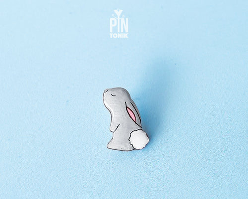 Hand-painted grey wooden bunny pin with a fluffy white tail and glossy resin finish
