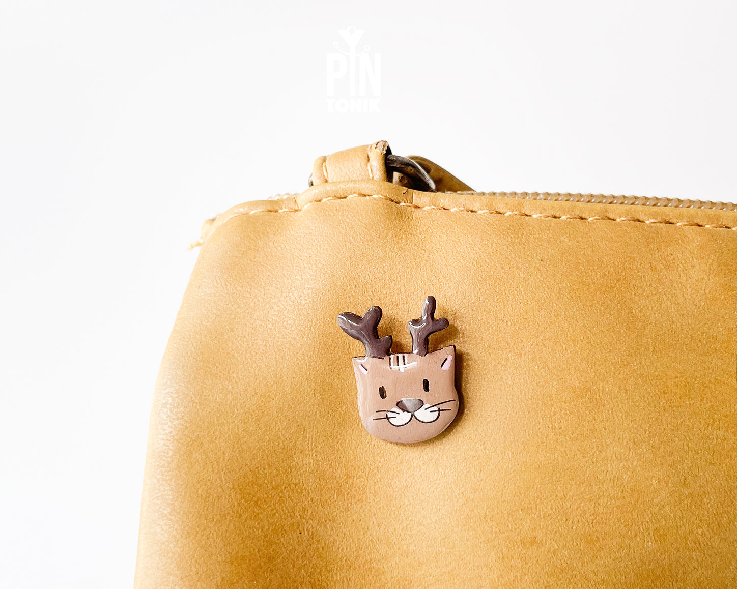Hand-painted wooden pin featuring a cute cat wearing reindeer antlers with a glossy resin finish