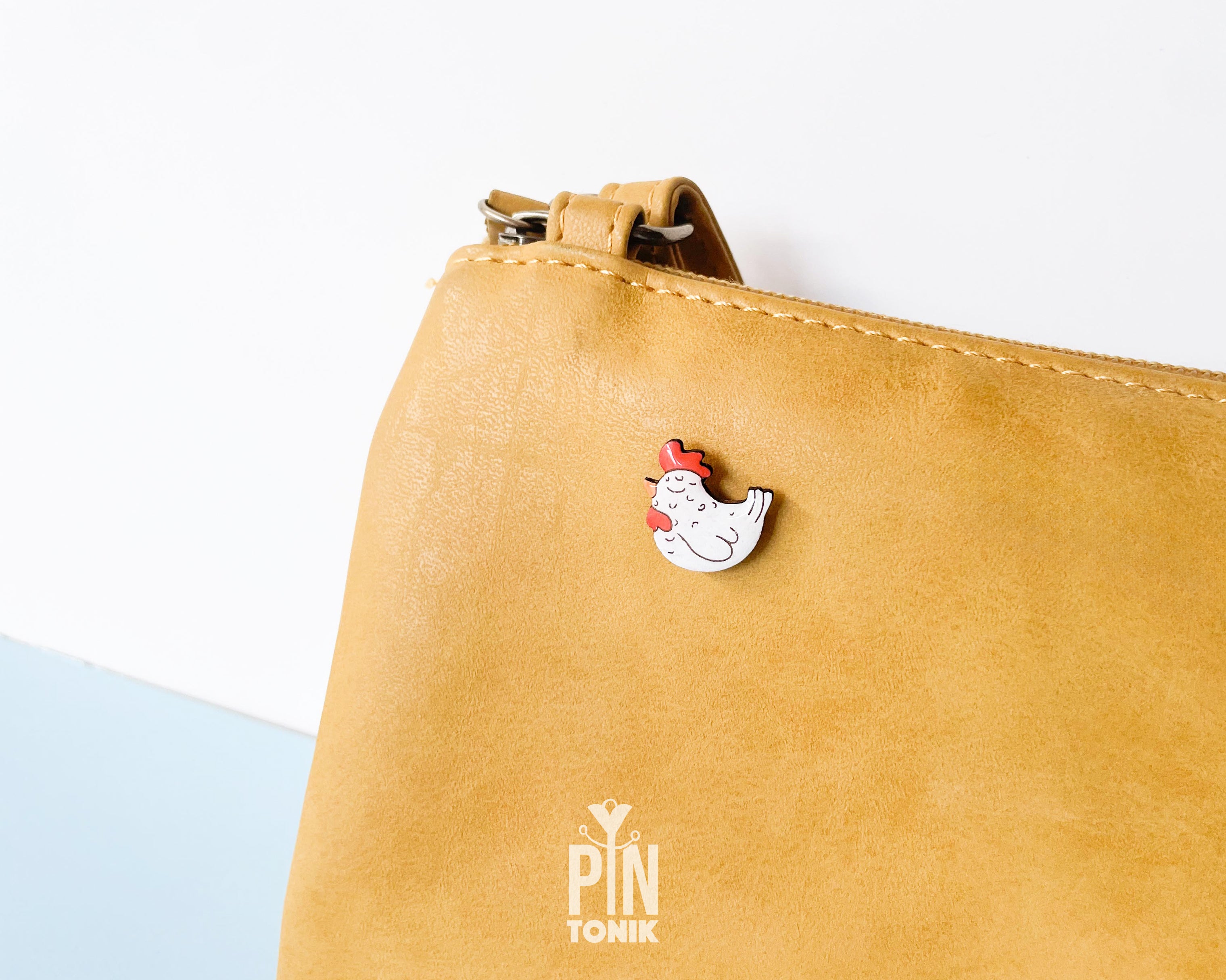 Hand-painted white wooden chicken pin with a red comb and a happy, eyes-closed expression, finished with glossy resin