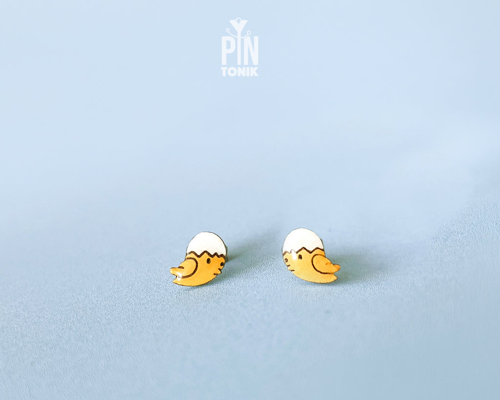 Handmade wooden hatching chick stud earrings with a tiny white eggshell on their head by PinTonik, cute spring and Easter themed jewelry.