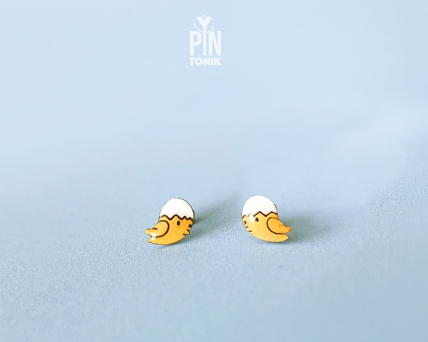 Handmade wooden hatching chick stud earrings with a tiny white eggshell on their head by PinTonik, cute spring and Easter themed jewelry.