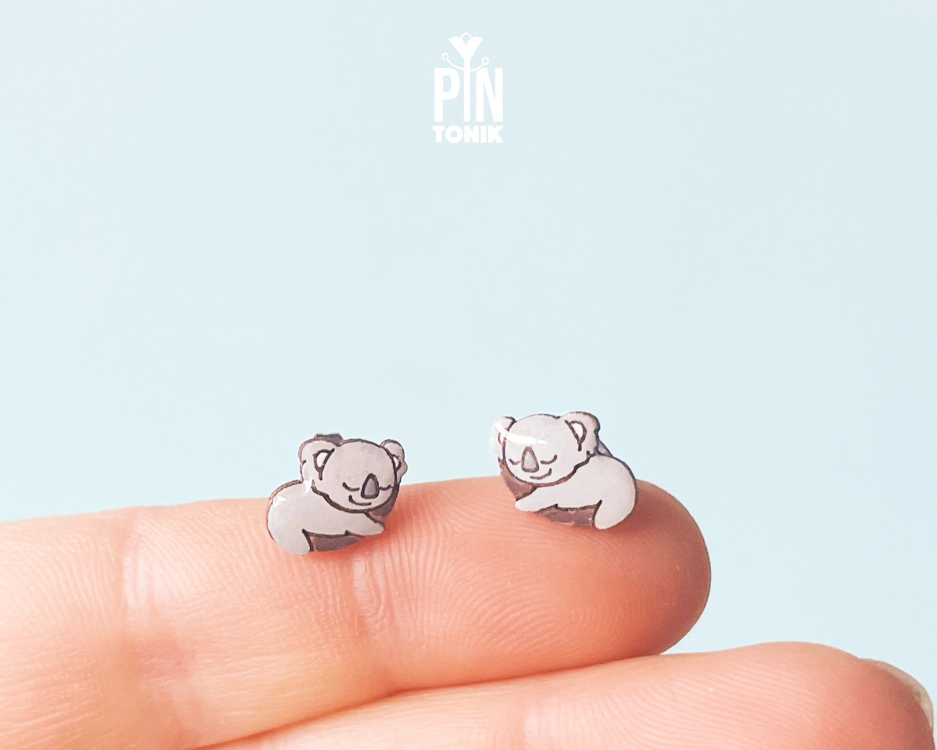 Pair of hand-painted wooden koala stud earrings featuring a sleeping design with closed eyes and pink ears