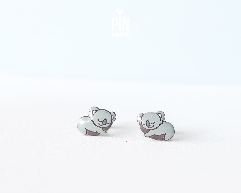 Pair of hand-painted wooden koala stud earrings featuring a sleeping design with closed eyes and pink ears