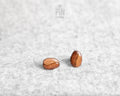 Handmade wooden roasted coffee bean stud earrings with a rich brown finish and realistic central fold detail by PinTonik.