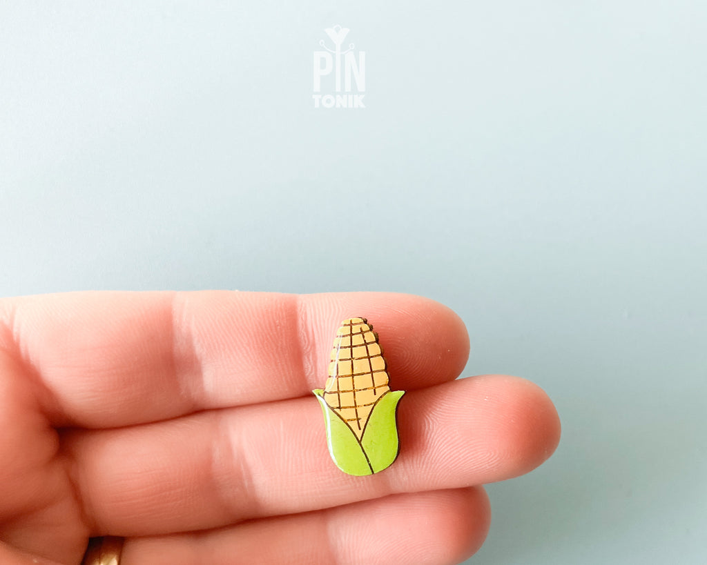 Hand-painted wooden pin of an ear of corn with bright green husks and a high-gloss resin finish