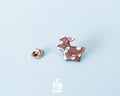 Hand-painted brown and white wooden cow pin with a pink flower and a glossy resin finish
