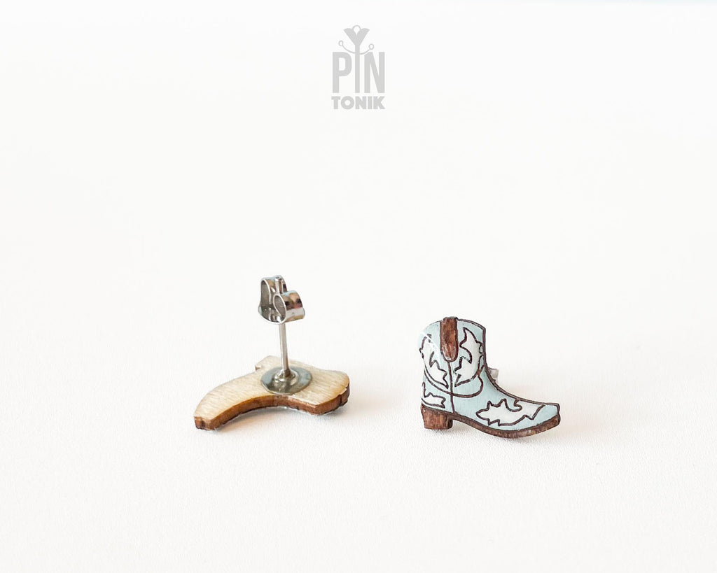 Handmade wooden cowboy boot stud earrings with detailed white and brown Western leather style illustrations by PinTonik.