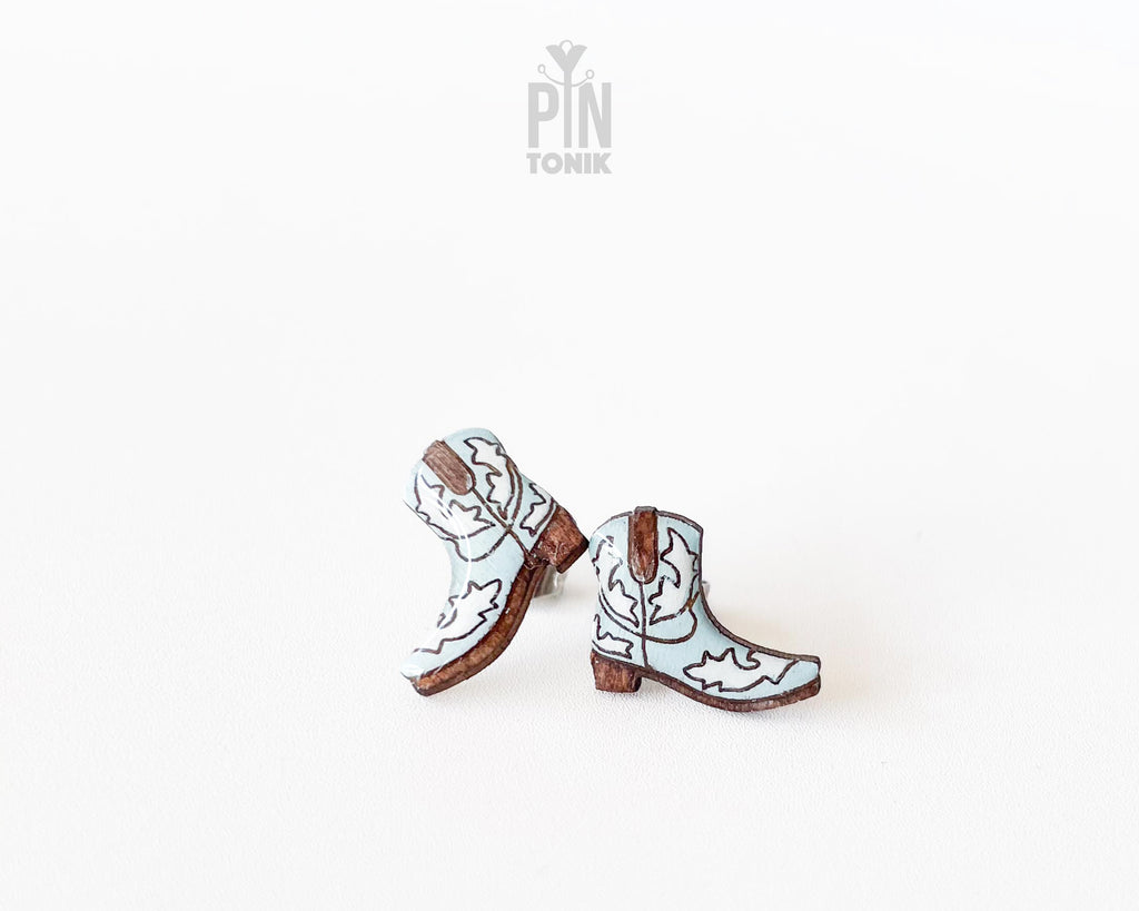 Handmade wooden cowboy boot stud earrings with detailed white and brown Western leather style illustrations by PinTonik.
