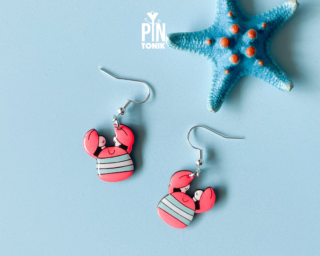 Hand-painted wooden crab dangle earrings with red pincers and grey-and-white striped bodies on sterling silver hooks