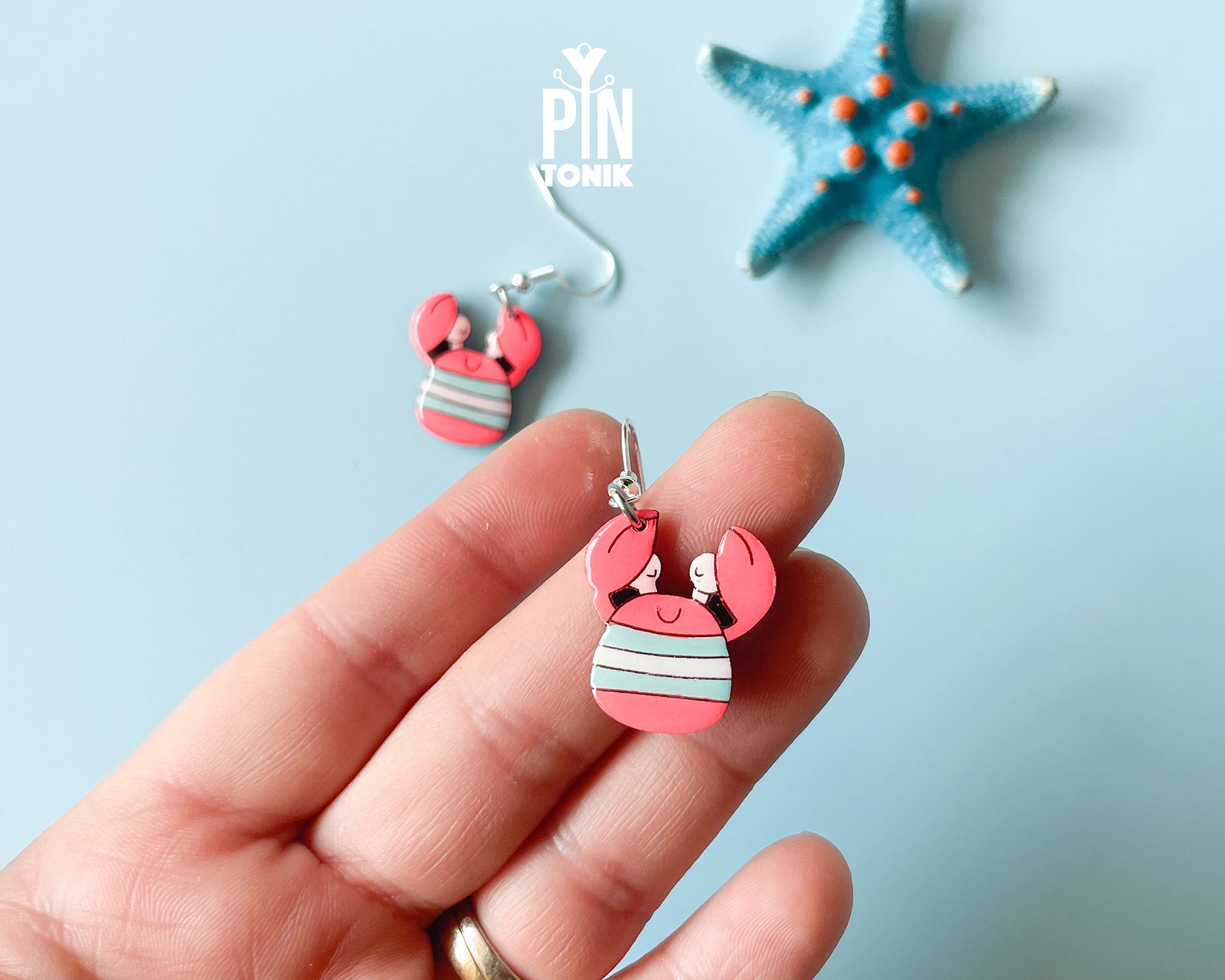 Hand-painted wooden crab dangle earrings with red pincers and grey-and-white striped bodies on sterling silver hooks