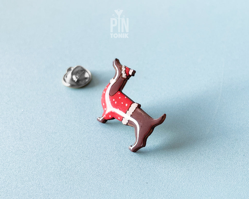 Hand-painted wooden dachshund pin wearing a red Christmas sweater and Santa hat with a glossy resin finish