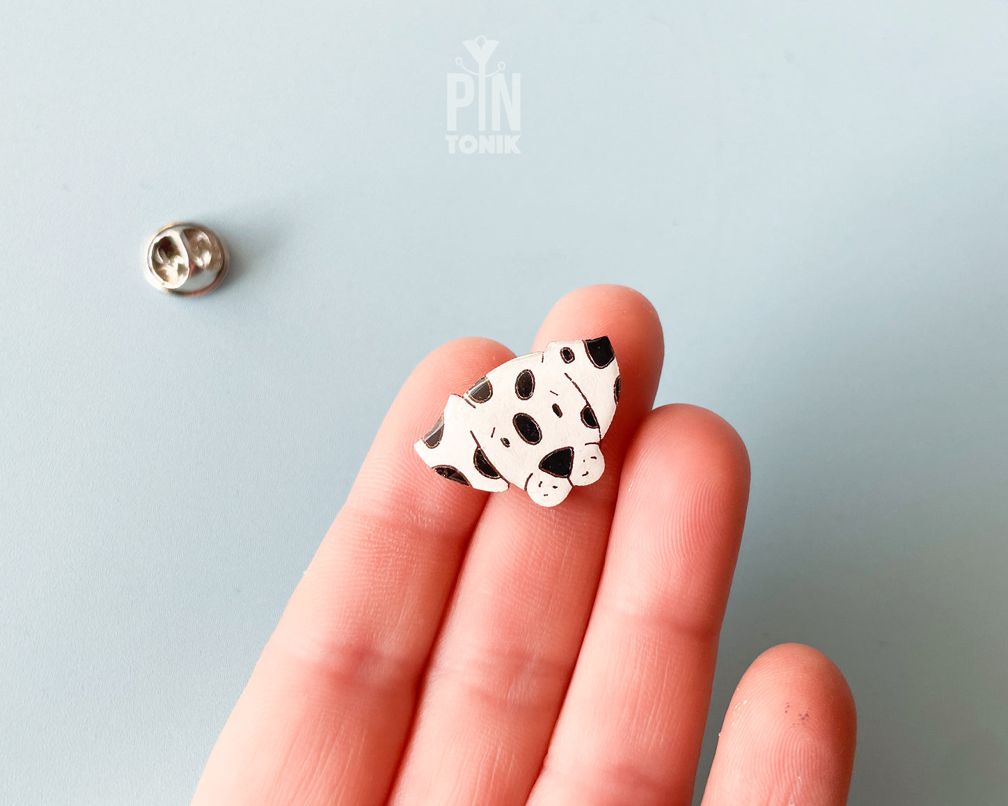 Hand-painted wooden dalmatian dog pin with black spots and a high-gloss resin finish