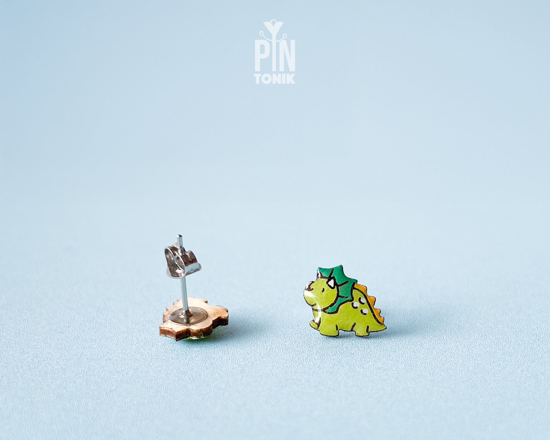 Pair of hand-painted green wooden triceratops dinosaur stud earrings with a high-gloss resin finish