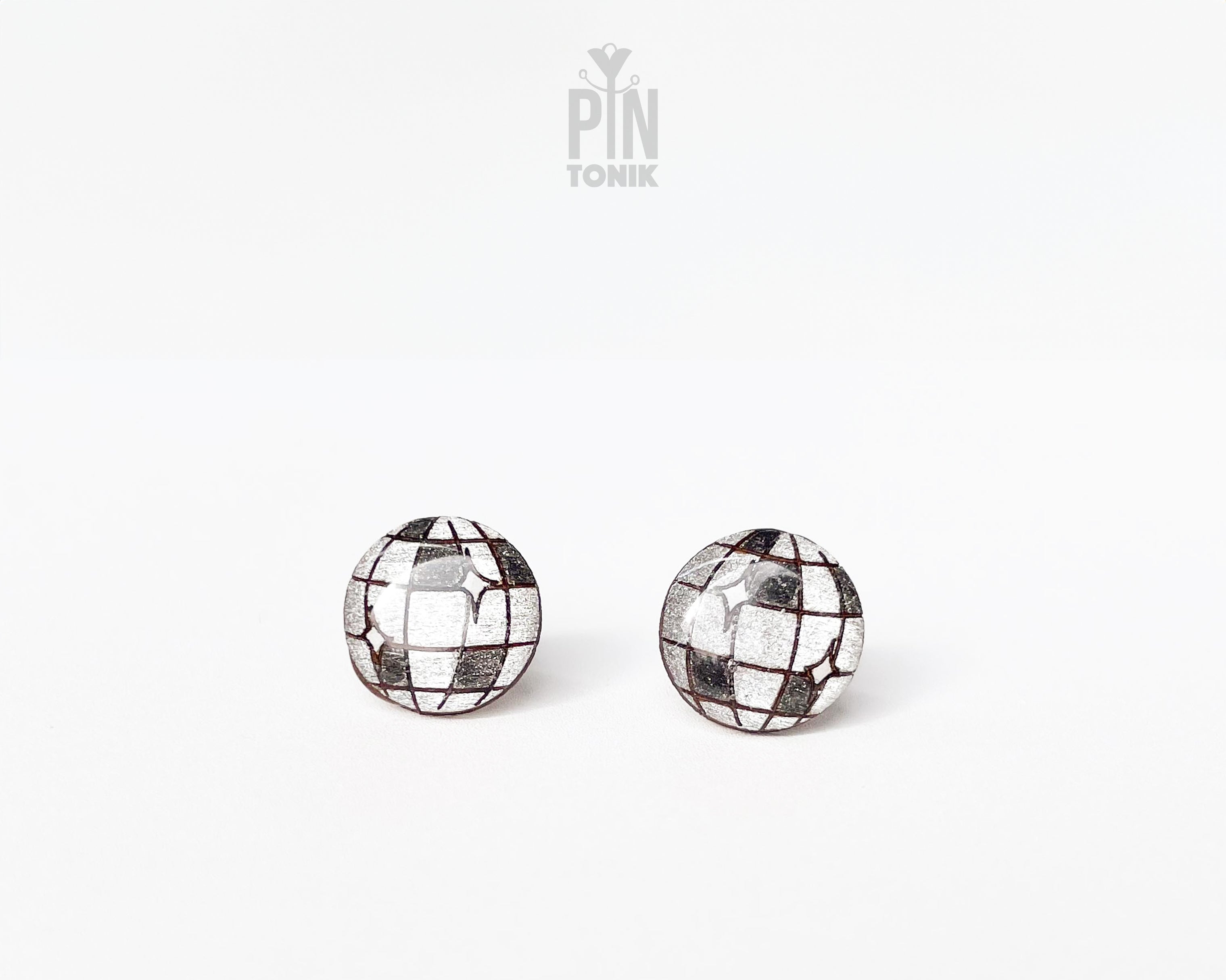 A pair of round stud earrings with a mirrored disco ball design, featuring reflective silver tiles and dark grid lines, shown on a plain white background with a 'PIN TONIK' watermark at the top.