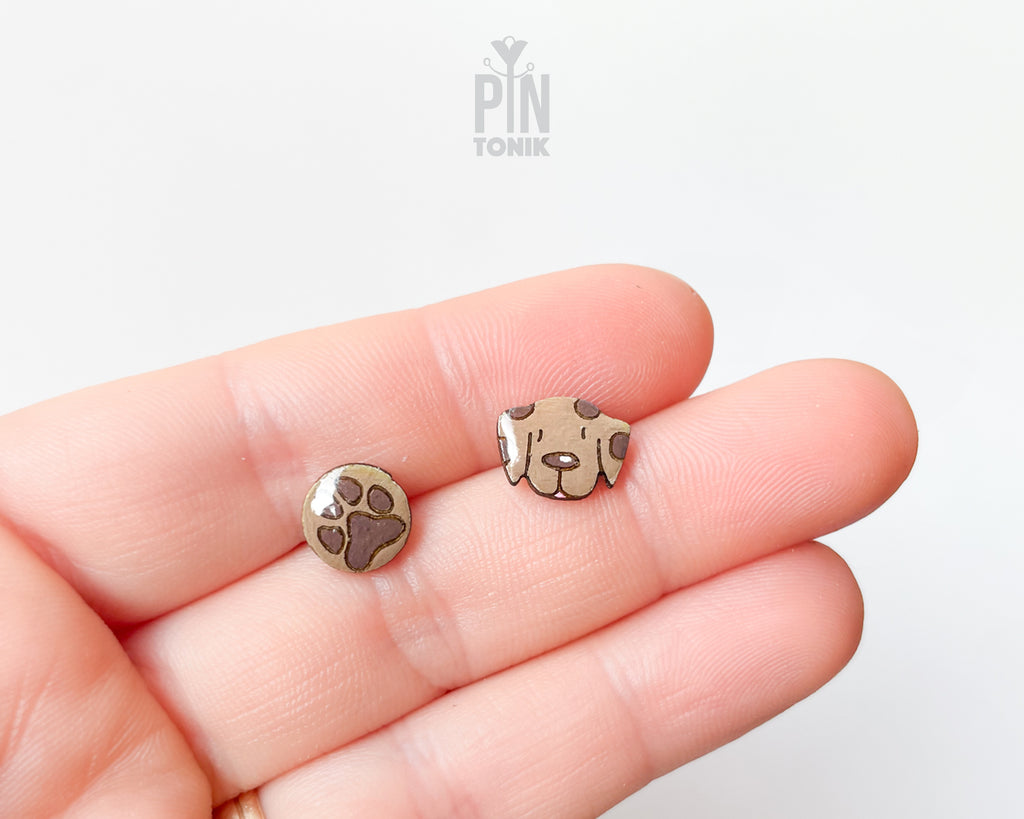 Mismatched hand-painted wooden stud earrings featuring a brown dog face and a matching paw print