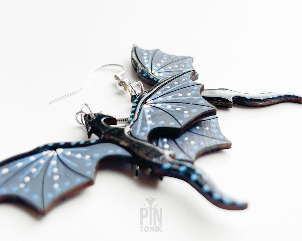 Hand-painted wooden Night dragon dangle earrings with sleek black bodies and speckled blue wing details on sterling silver hooks