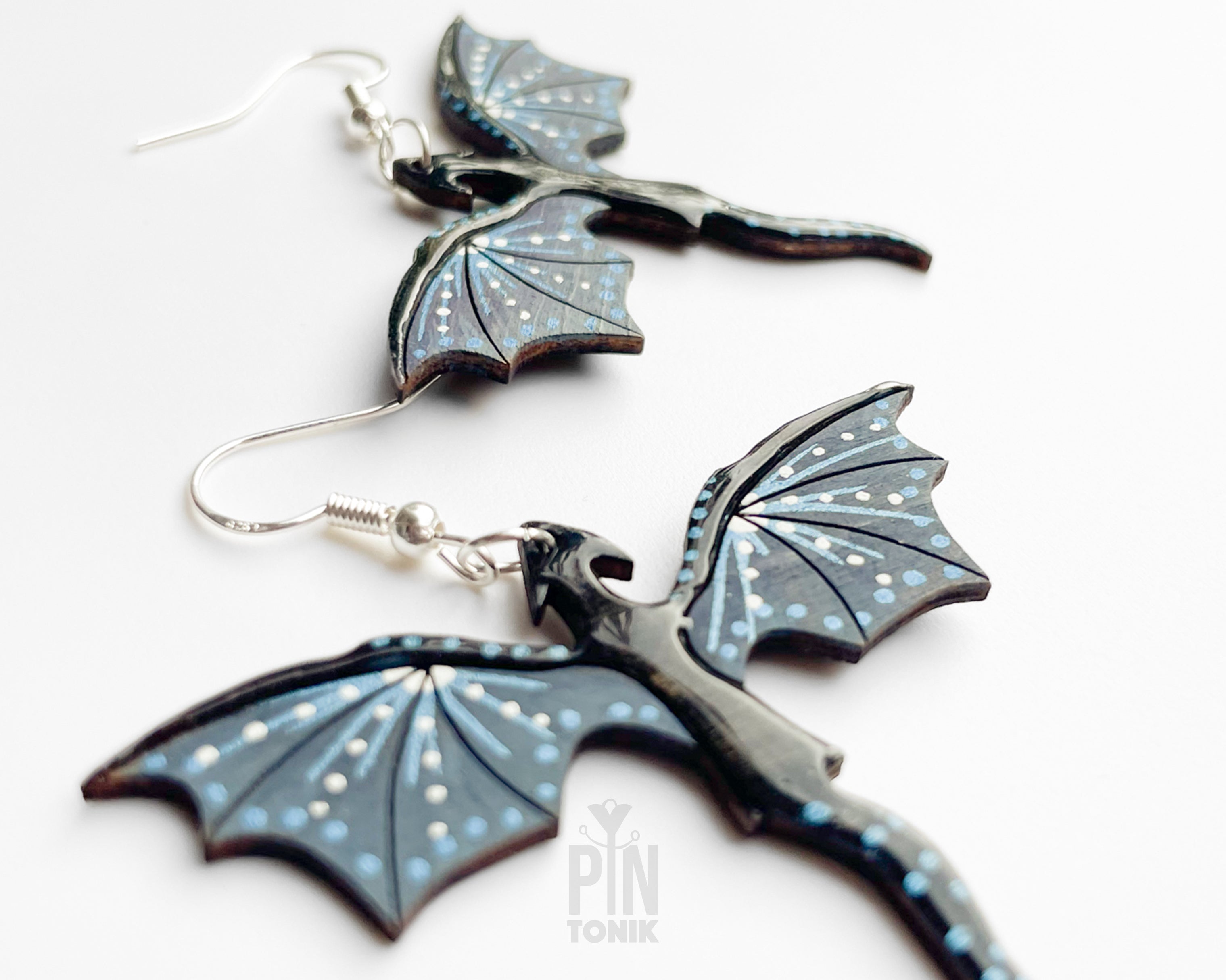 Hand-painted wooden Night dragon dangle earrings with sleek black bodies and speckled blue wing details on sterling silver hooks