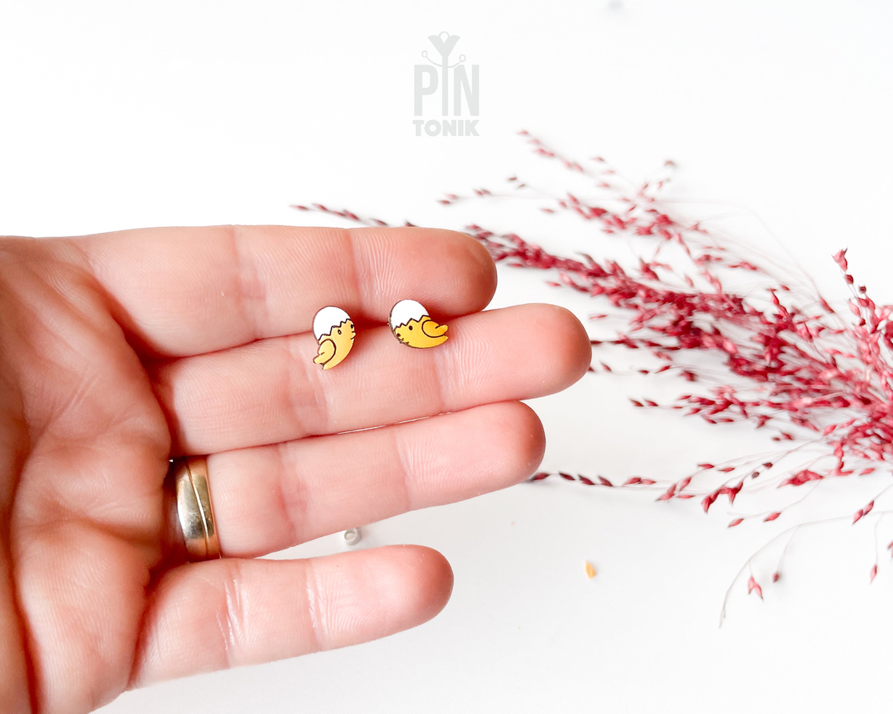 Handmade wooden hatching chick stud earrings with a tiny white eggshell on their head by PinTonik, cute spring and Easter themed jewelry.