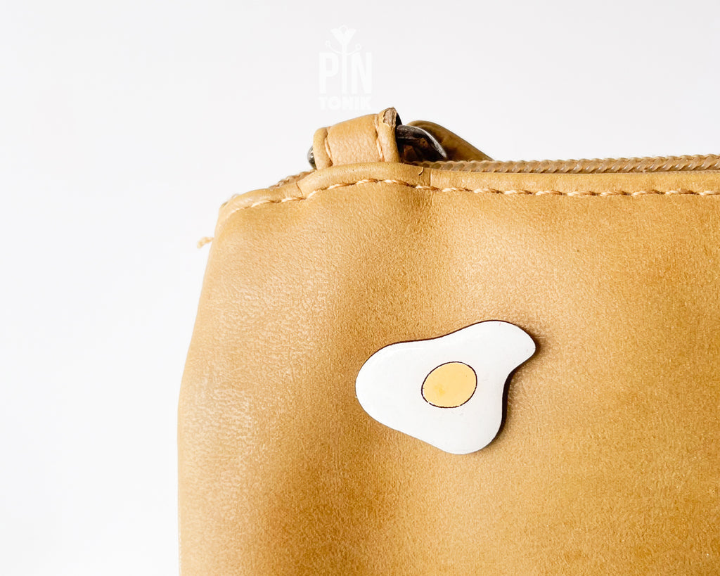 Hand-painted wooden fried egg pin with a bright yellow yolk and white egg white