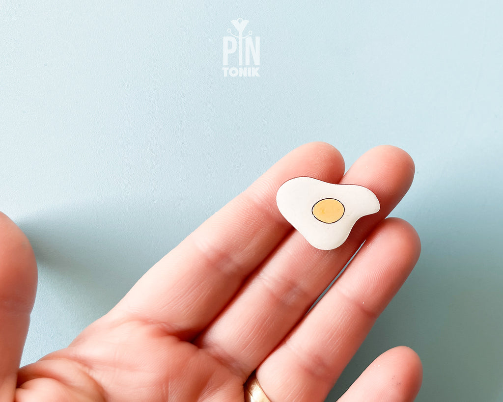 Hand-painted wooden fried egg pin with a bright yellow yolk and white egg white