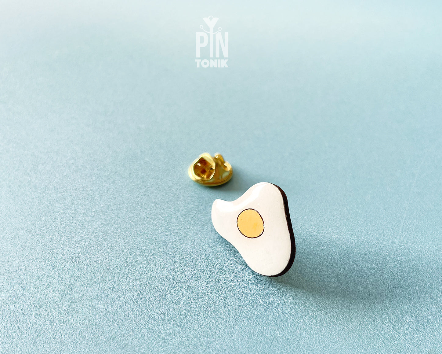 Hand-painted wooden fried egg pin with a bright yellow yolk and white egg white