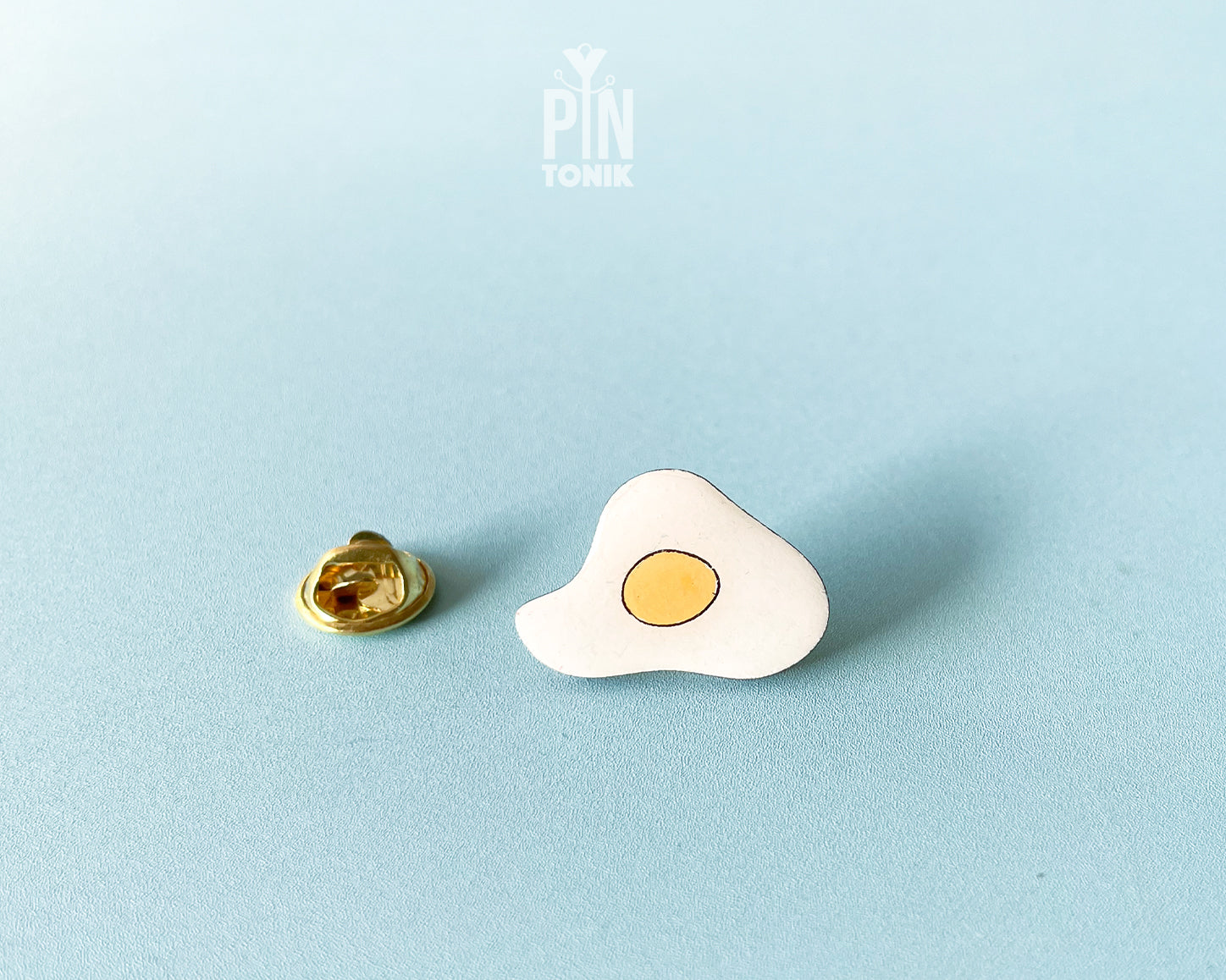 Hand-painted wooden fried egg pin with a bright yellow yolk and white egg white