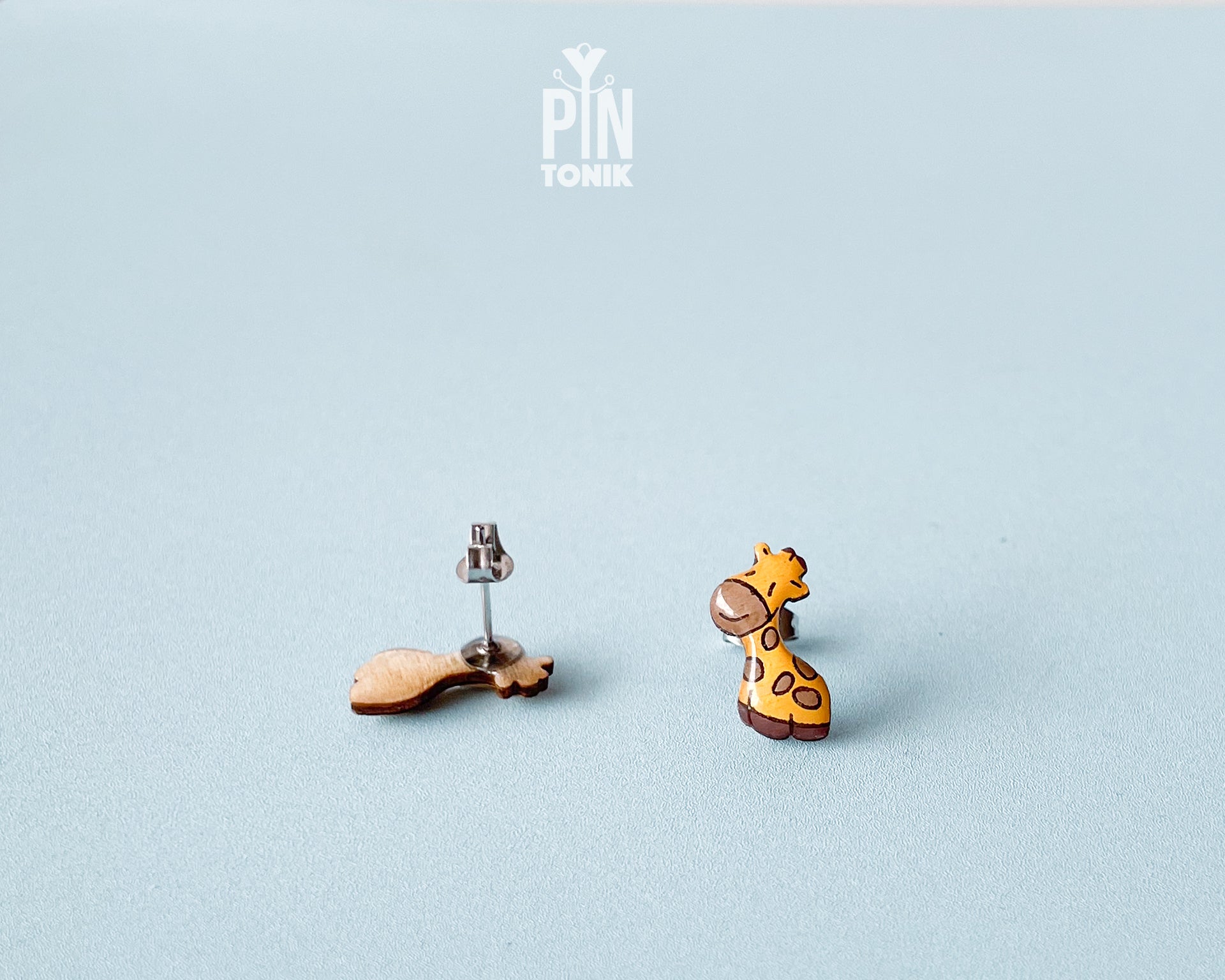 Pair of hand-painted wooden giraffe stud earrings with a glossy resin finish and sleepy expressions