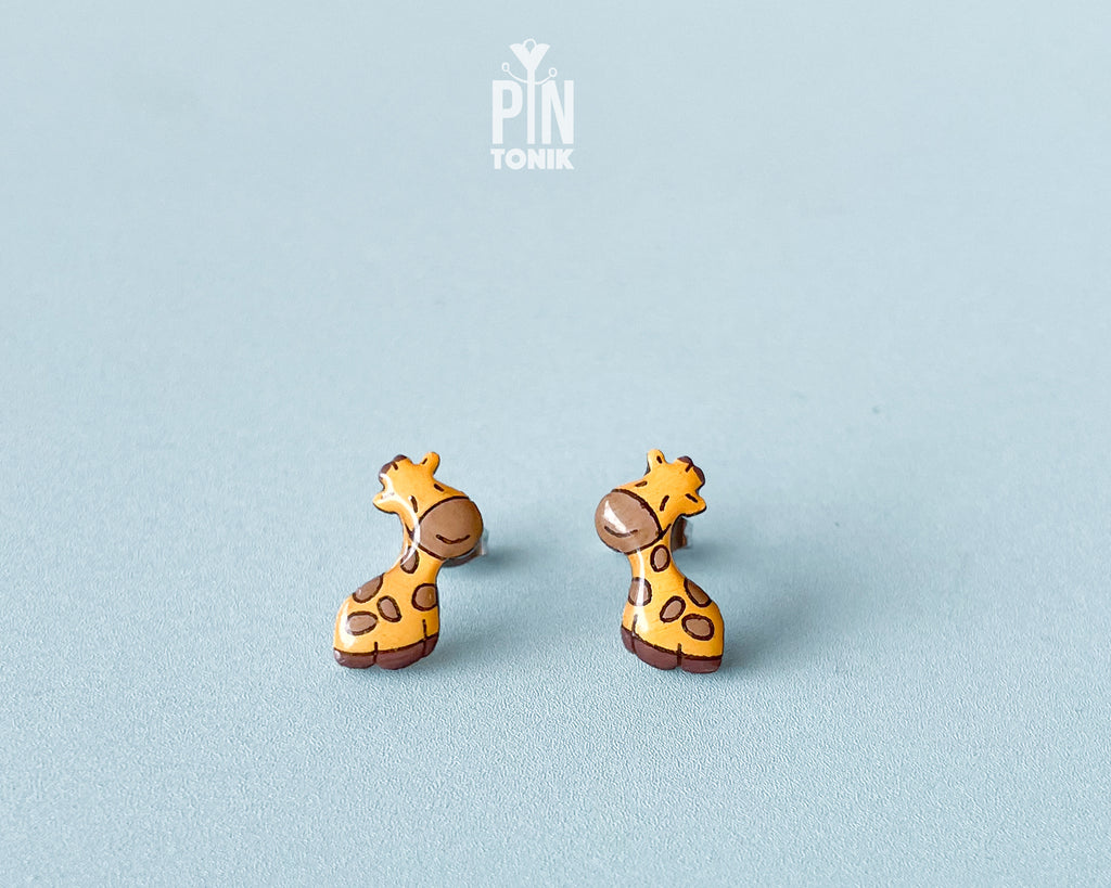 Pair of hand-painted wooden giraffe stud earrings with a glossy resin finish and sleepy expressions