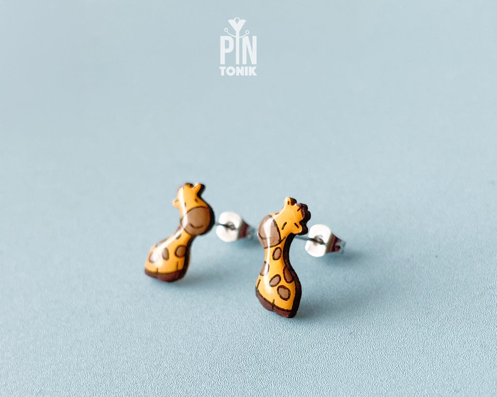 Pair of hand-painted wooden giraffe stud earrings with a glossy resin finish and sleepy expressions
