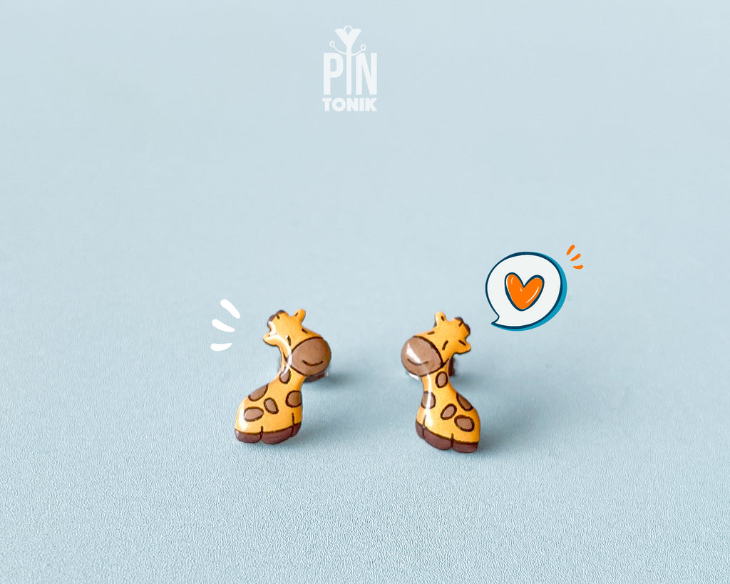 Pair of hand-painted wooden giraffe stud earrings with a glossy resin finish and sleepy expressions